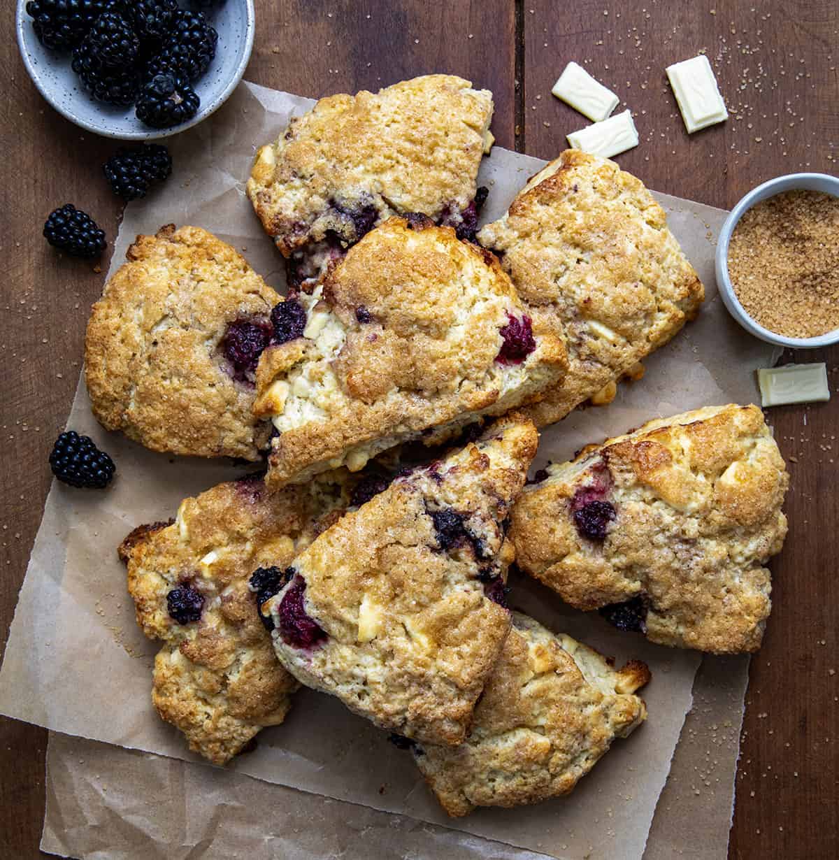 Blackberry White Chocolate Scones on brown parchment paper on a wooden table from overhead.