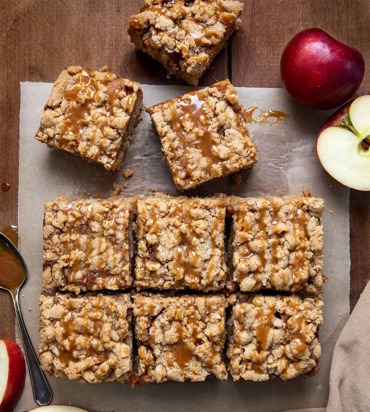 Caramel Apple Crumb Cake cut into slices on parchment paper on a wooden table from overhead.