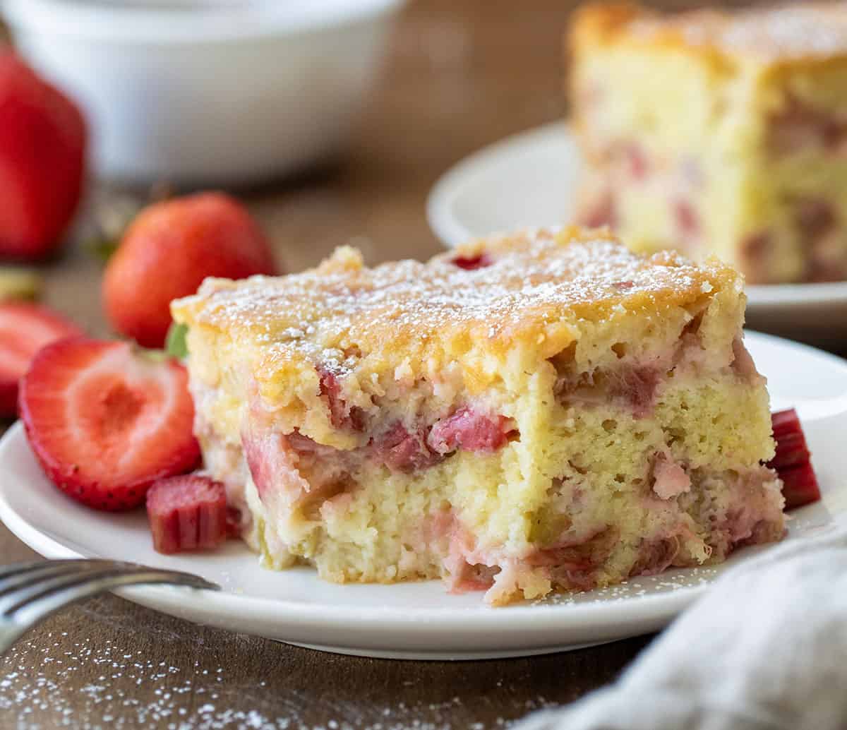 Fresh Strawberry Rhubarb Cake is a soft, moist cake loaded with fresh strawberries and rhubarb, perfect for a summertime treat, dessert, or breakfast cake. I love to have a piece with my cup of coffee! Piece of Fresh Strawberry Rhubarb Cake with a bite removed and the fork resting on the white plate.
