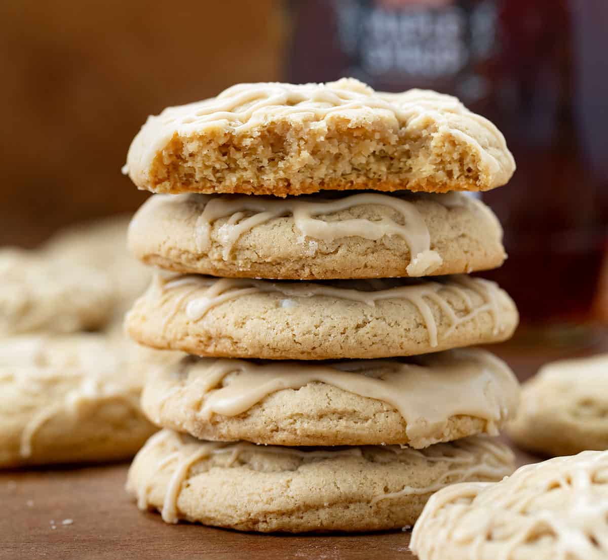 Stack of Maple Brown Sugar Cookies on a wooden table with top cookie broken in half showing tender crumb inside.