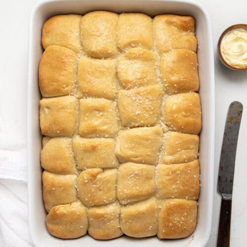 Parker House Rolls in a white casserole dish on a white table from overhead.