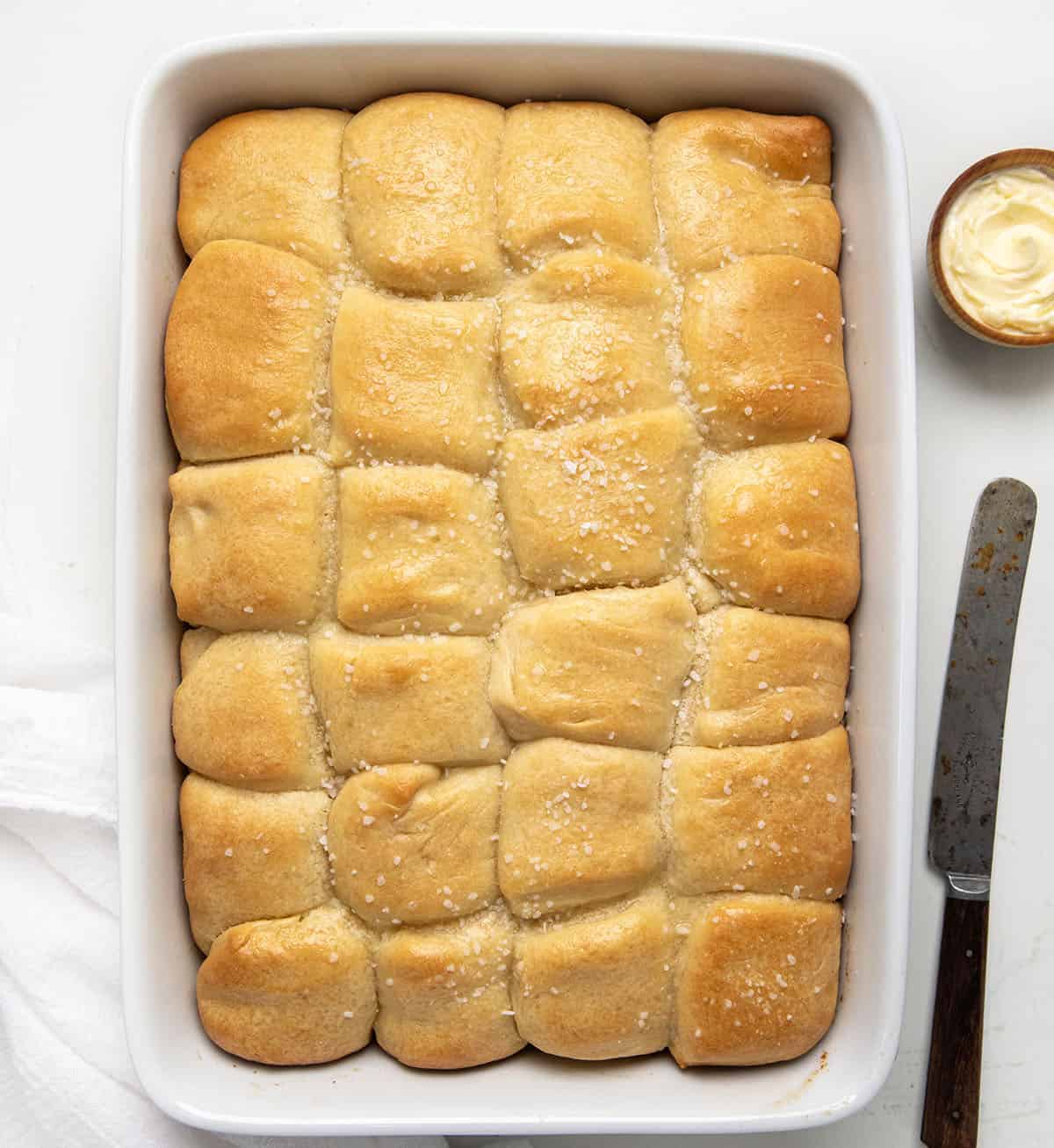 Parker House Rolls in a white casserole dish on a white table from overhead.