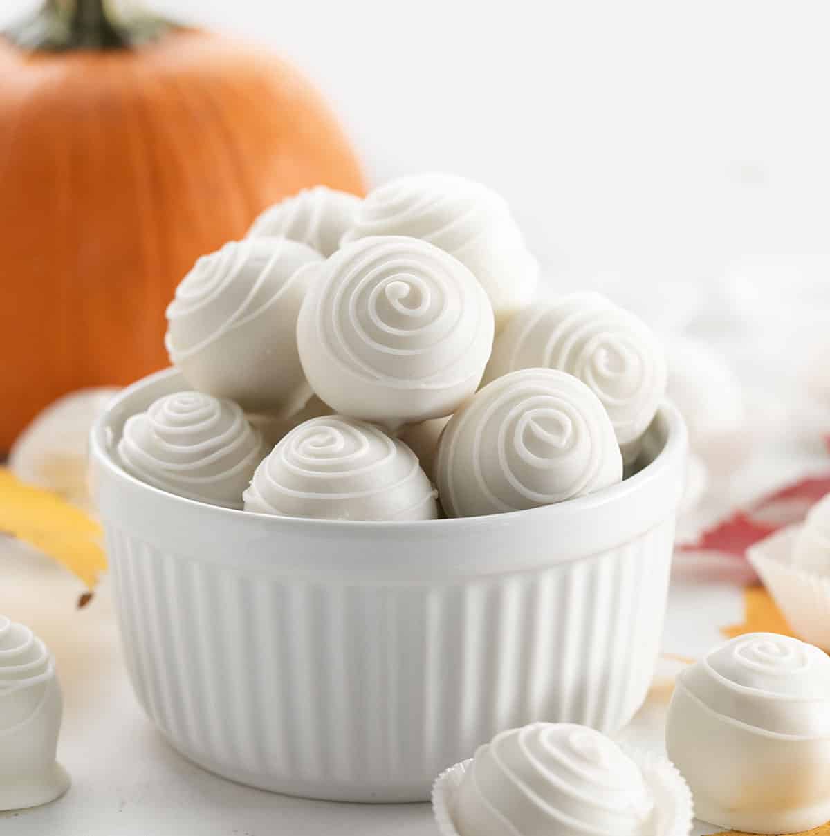 Bowl of Pumpkin Truffles on a table with autumn leaves.