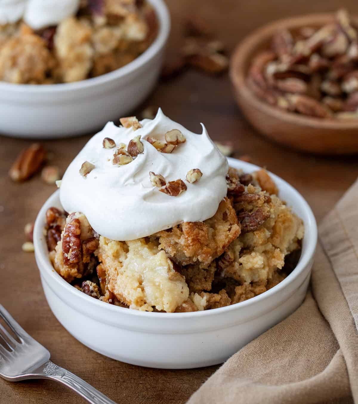 Bowls of Sweet Potato Dump Cake on a wooden table with napkin and fork.