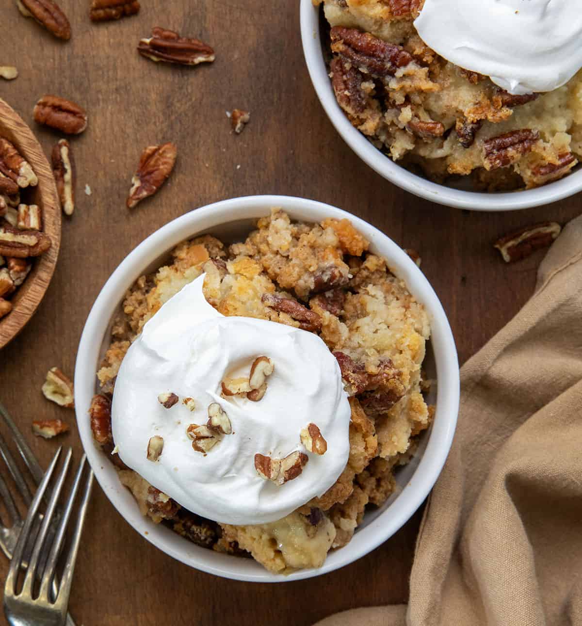 Bowls of Sweet Potato Dump Cake on a wooden table with napkin and fork.