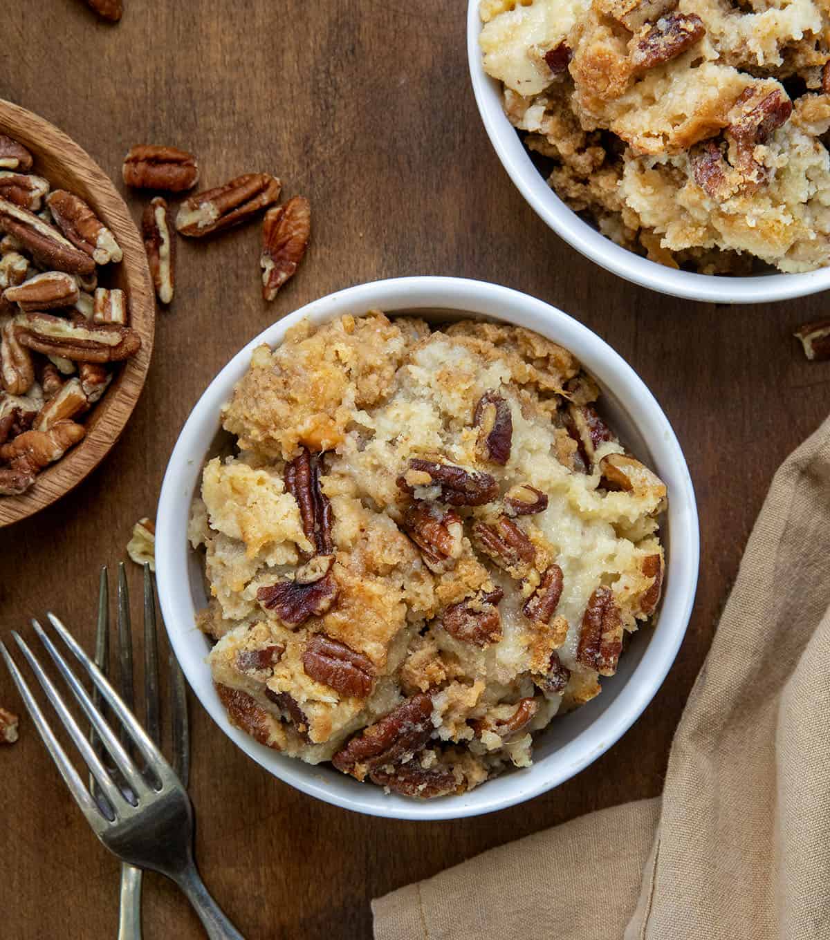 Bowls of Sweet Potato Dump Cake on a wooden table with napkin and fork.