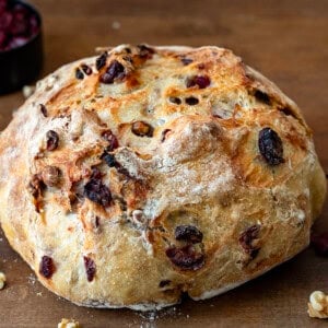 Whole Cranberry Walnut Bread on a wooden table close up.