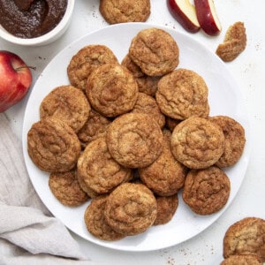 Plate of Apple Butter Snickerdoodles on a white table with apple butter and apples from overhead.