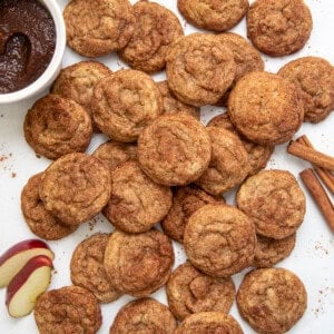 Apple Butter Snickerdoodles on a white table with apple butter, apples, and cinnamon sticks from overhead.