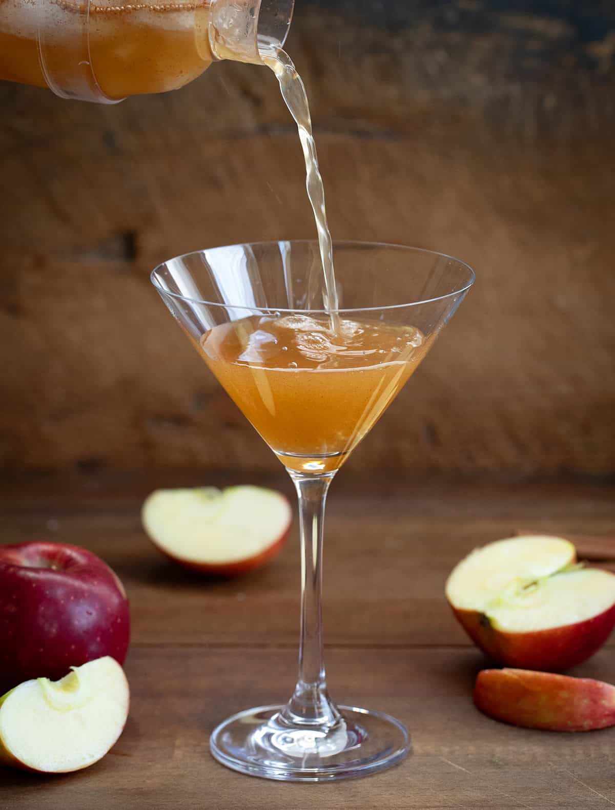 Pouring Apple Cider cocktail into a martini glass.