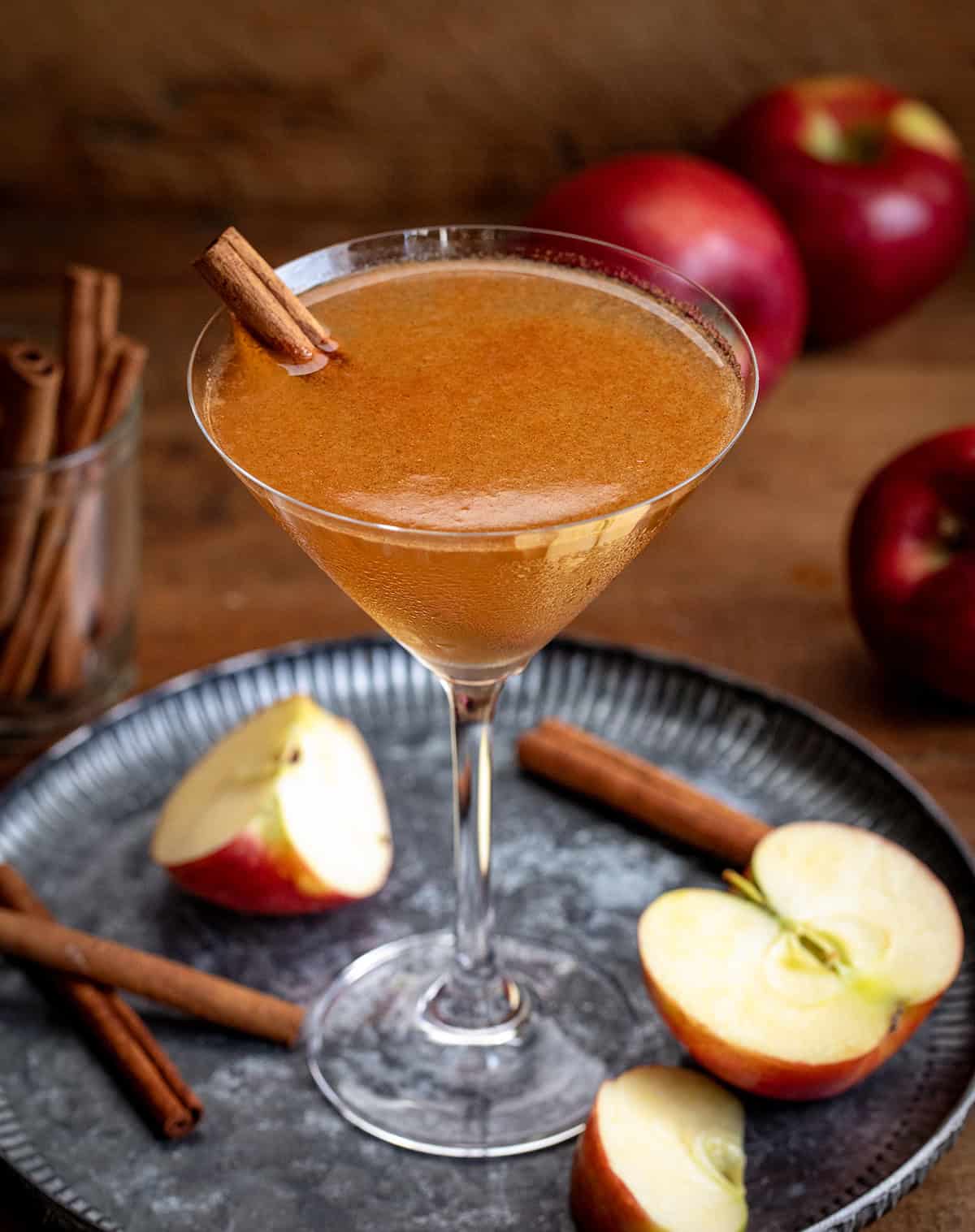 Apple Cider Martini on a tray with apples and cinnamon sticks.