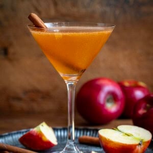 Apple Cider Martini on a tray with apples and cinnamon sticks.