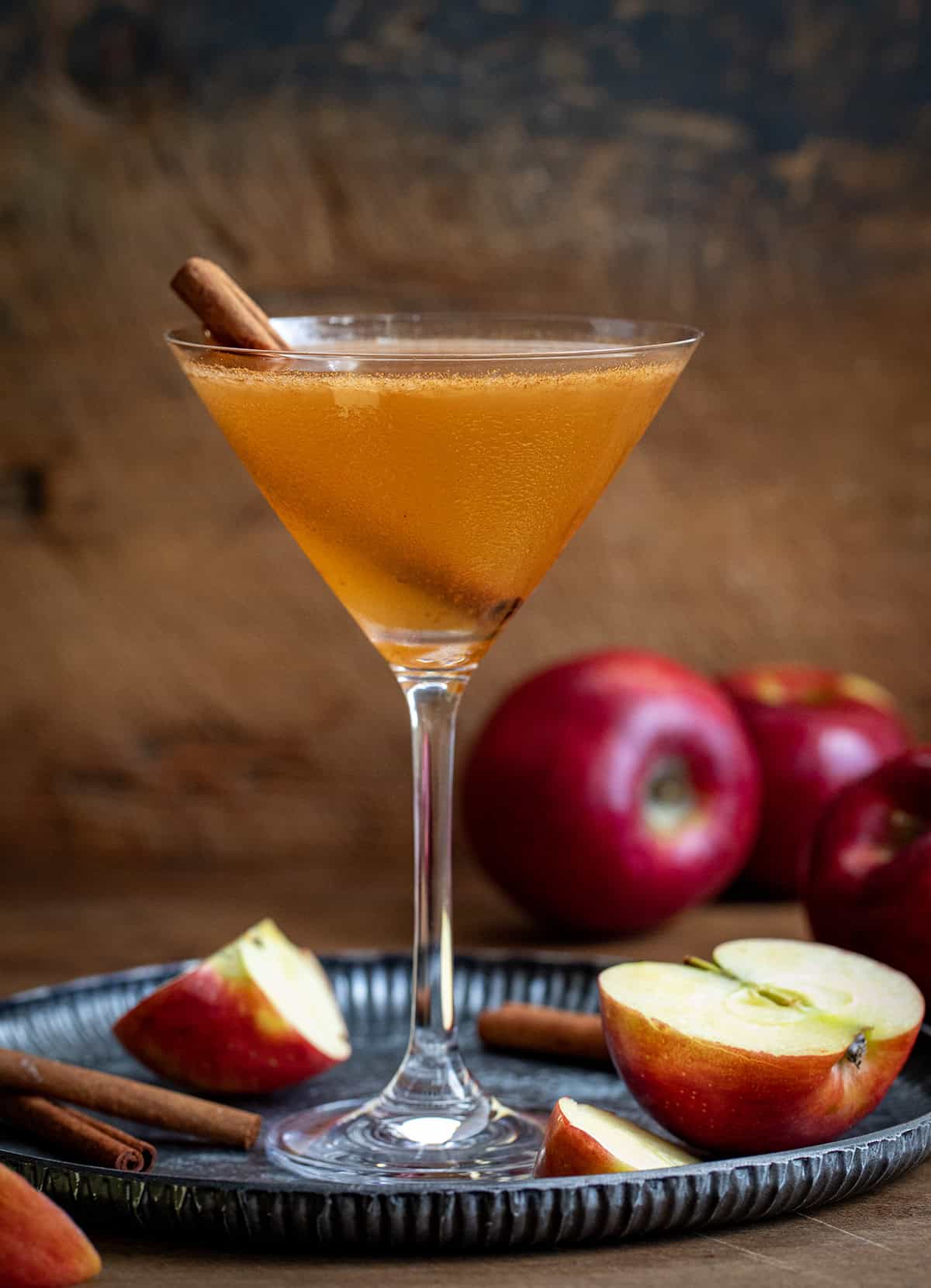 Apple Cider Martini on a tray with apples and cinnamon sticks. 