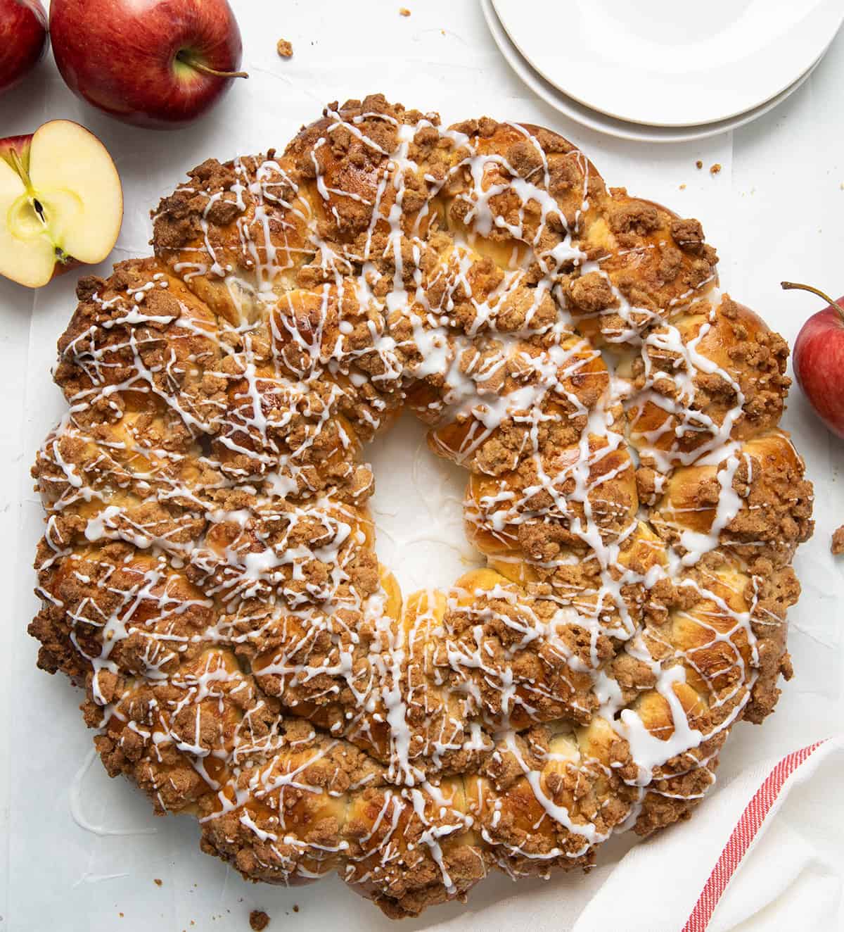 Apple Pie Bomb Wreath on a white table with apples and plates from overhead.