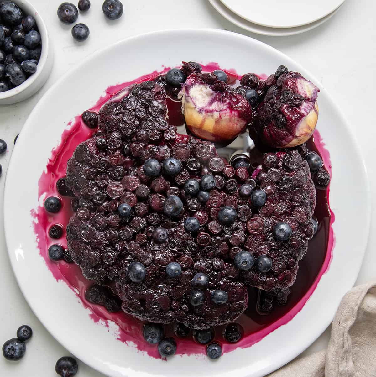 Baked Cream Cheese Blueberry Bombs on a white platter with a couple of blueberry bombs torn off.