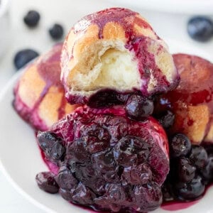 Halved Baked Cream Cheese Blueberry Bomb on a plate with other blueberry bombs.