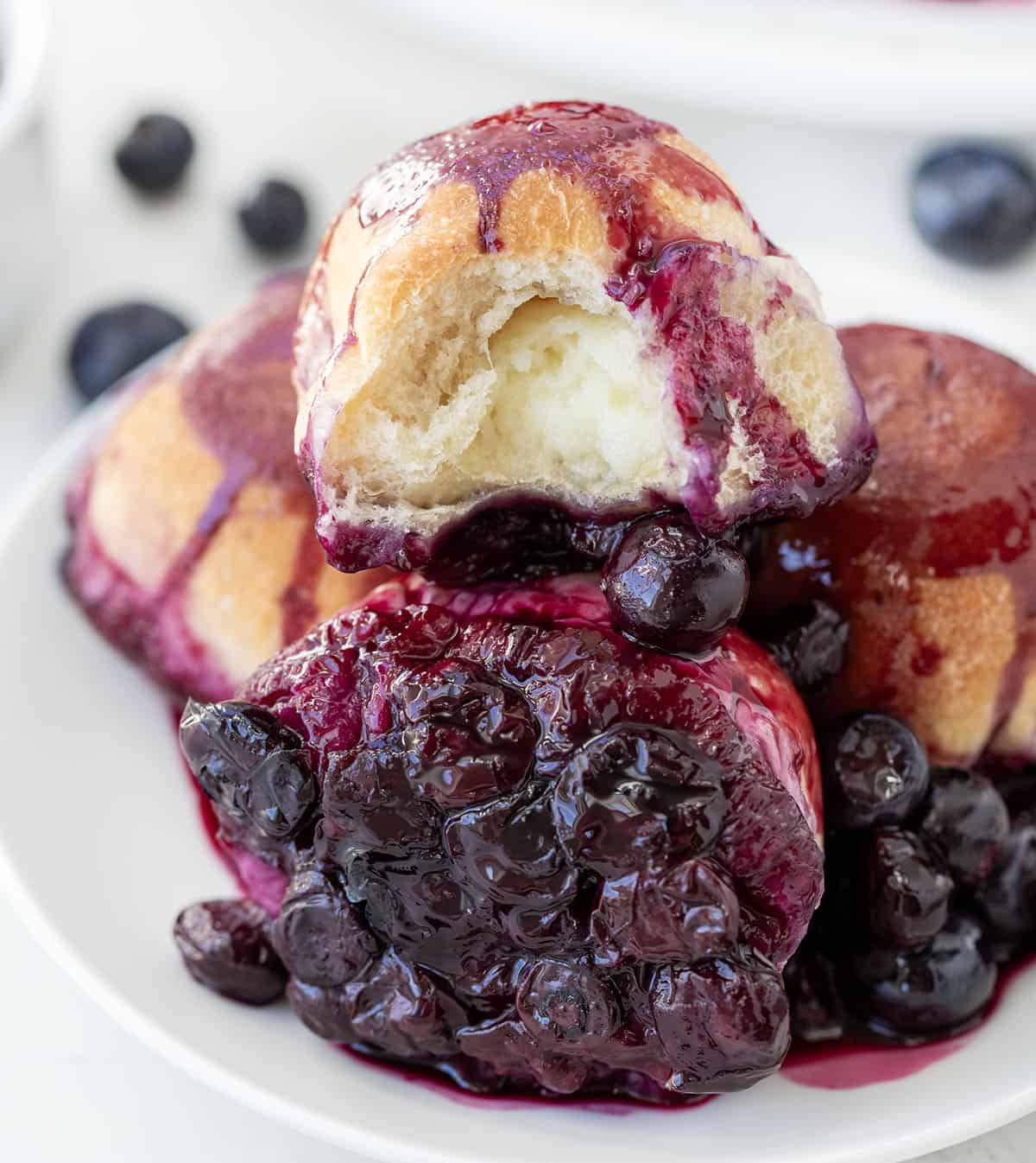 Halved Baked Cream Cheese Blueberry Bomb on a plate with other blueberry bombs.