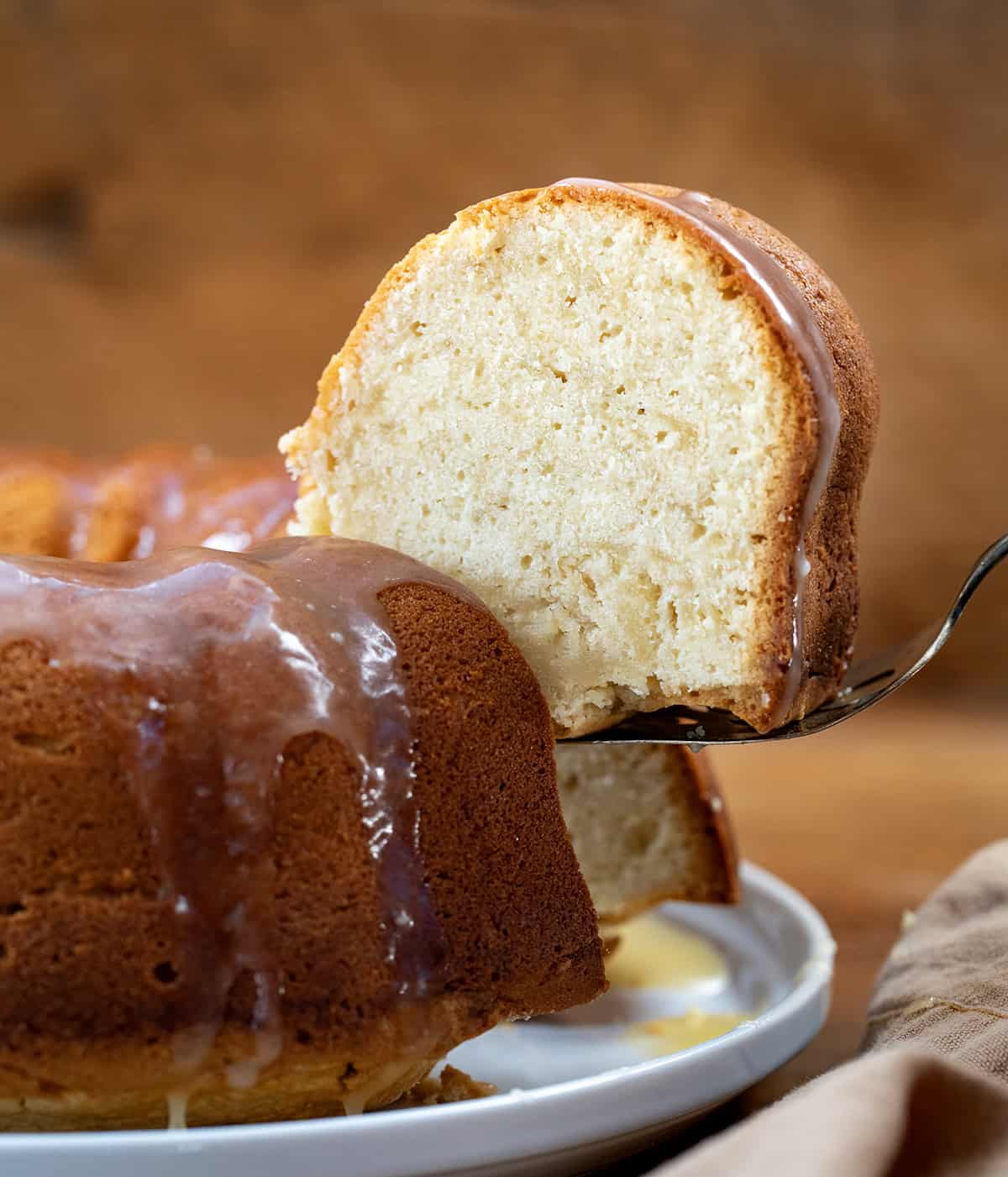 Picking up a piece of Brown Sugar Maple Pound Cake from the cake platter close up.