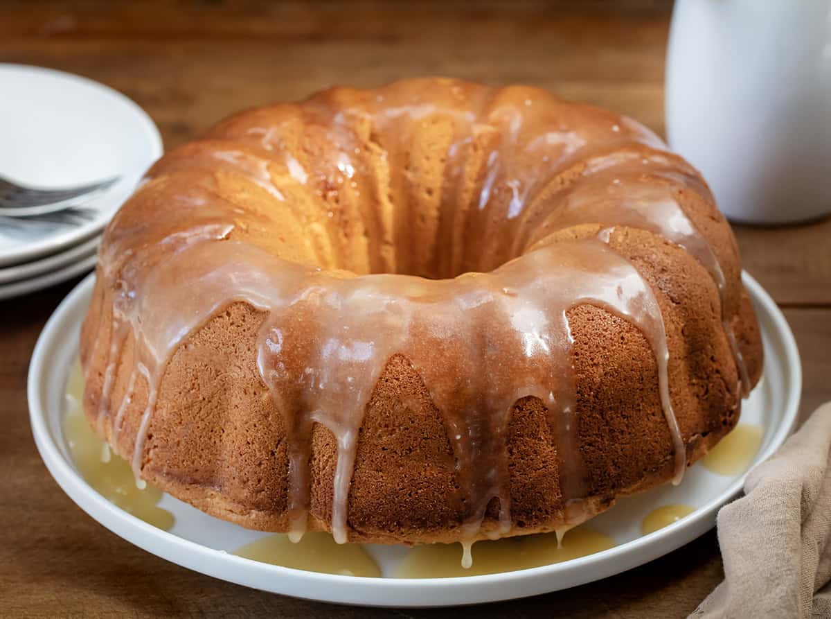 Brown Sugar Maple Pound Cake on a white cake plate on a wooden table.