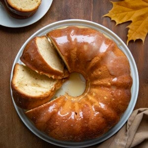 Brown Sugar Maple Pound Cake on a white cake plate with 2 pieces cut and leaning on their side from overhead.