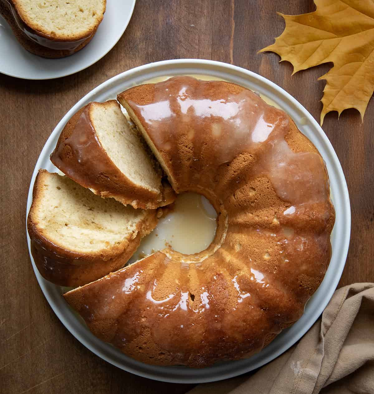 Brown Sugar Maple Pound Cake on a white cake plate with 2 pieces cut and leaning on their side from overhead.