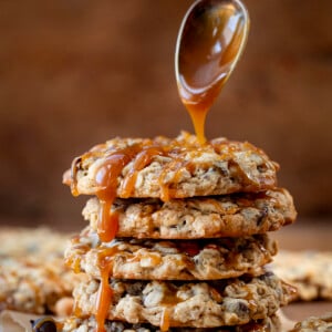 Drizzling caramel over Carmelita Cookies on a wooden table.