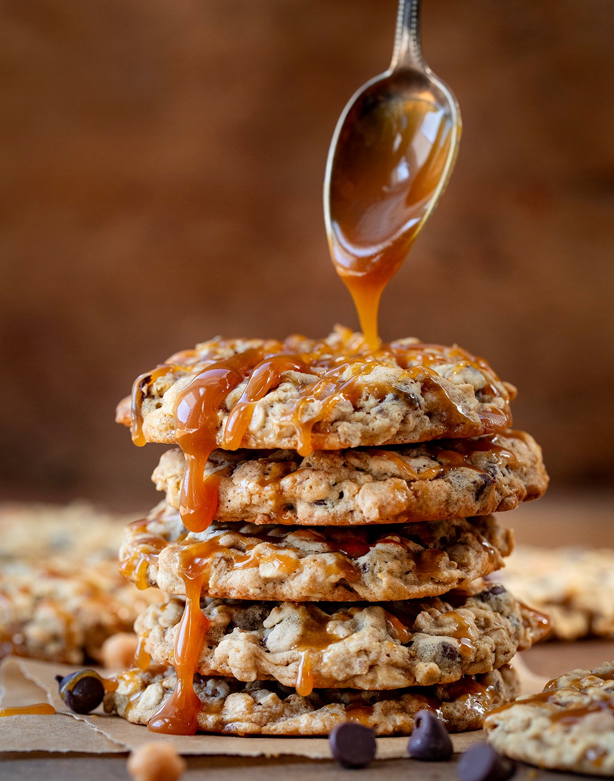 Drizzling caramel over Carmelita Cookies on a wooden table.