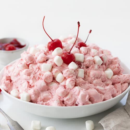 Big white bowl filled with Cherry Cheesecake Fluff with mini marshmallows and cherries.