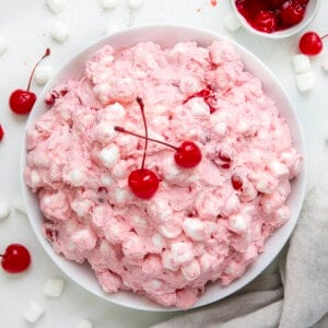 Big white bowl filled with Cherry Cheesecake Fluff with mini marshmallows and cherries.