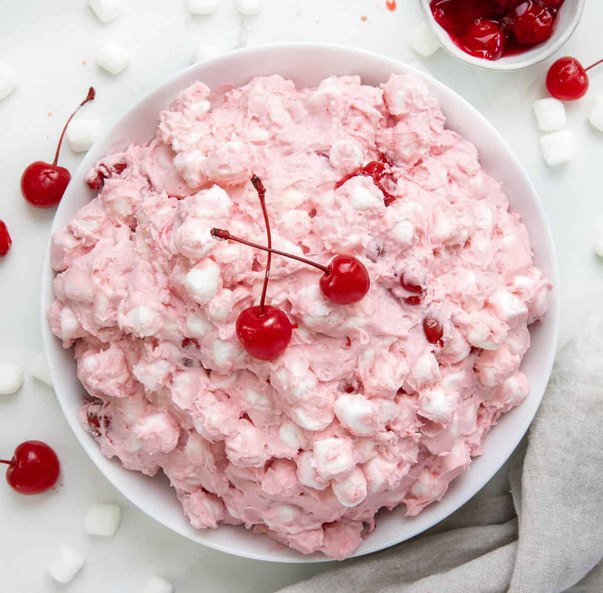 Big white bowl filled with Cherry Cheesecake Fluff with mini marshmallows and cherries.