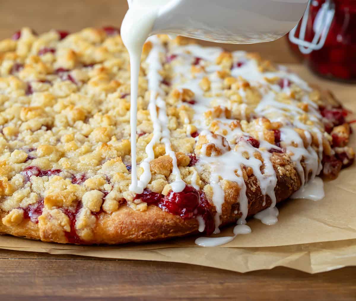 Drizzling glaze over a Cherry Dessert Pizza.