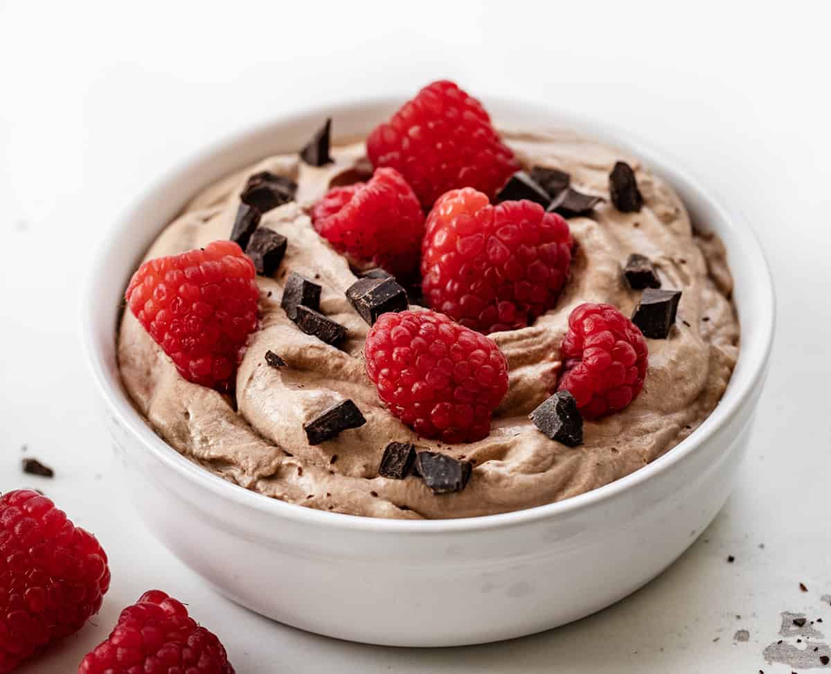 Bowl of Chocolate Stabilized Whipped Cream with raspberries and chopped chocolate.