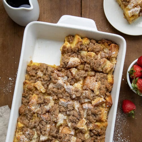 Overnight French Toast Casserole in pan on a wooden table with one piece taken out.