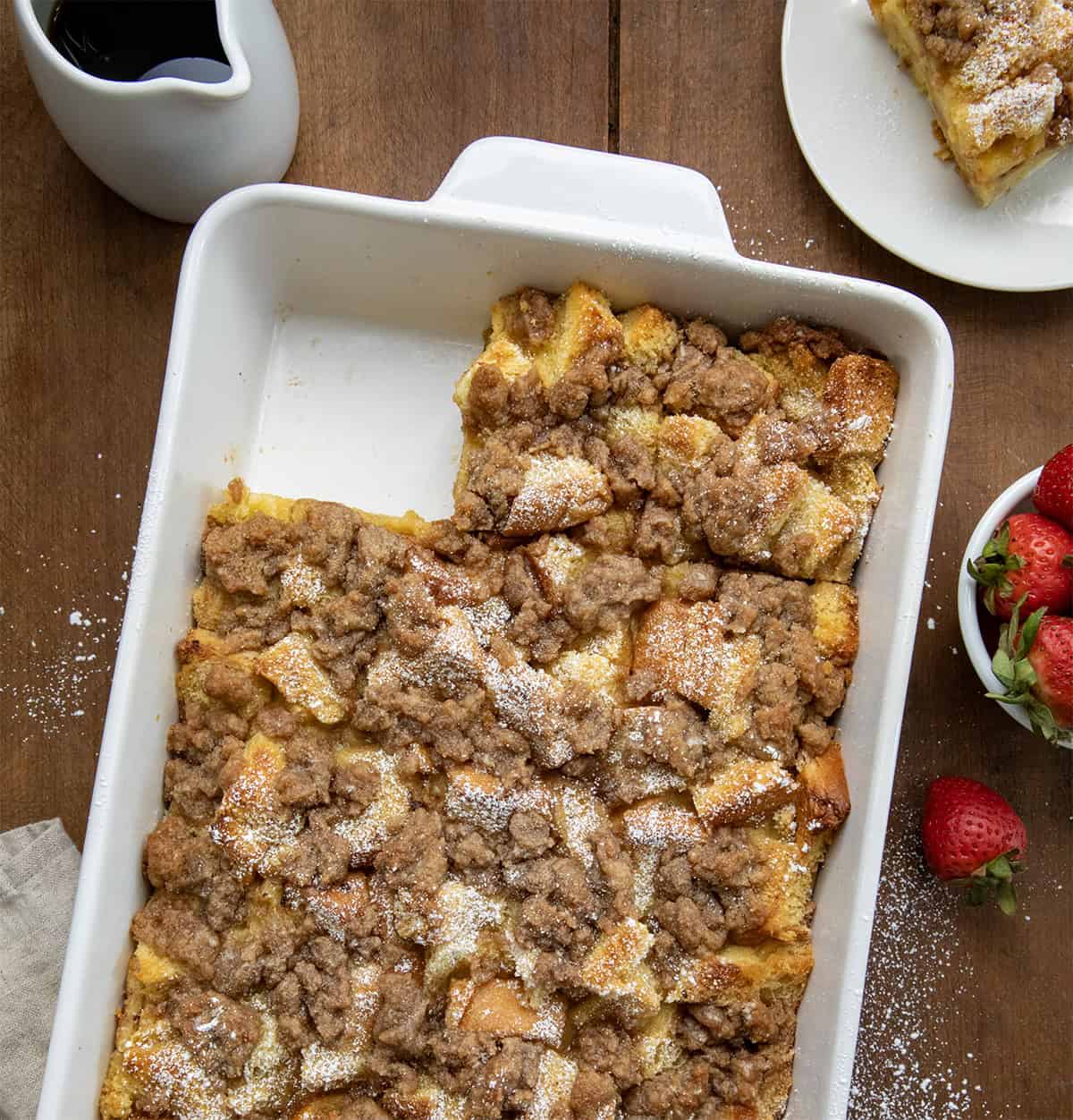 Overnight French Toast Casserole in pan on a wooden table with one piece taken out.