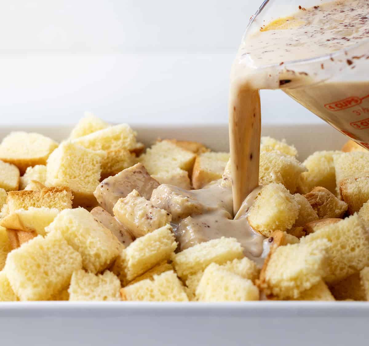 Pouring egg mixture over brioche bread to make Overnight French Toast Casserole.