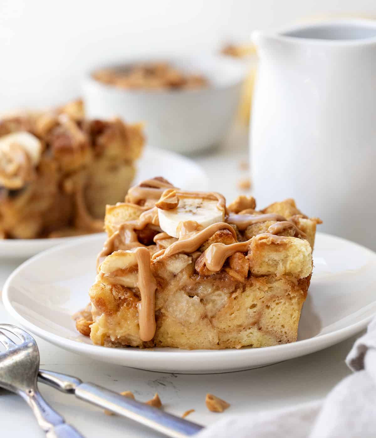 White plates with Peanut Butter Banana Overnight French Toast on them on a white table.