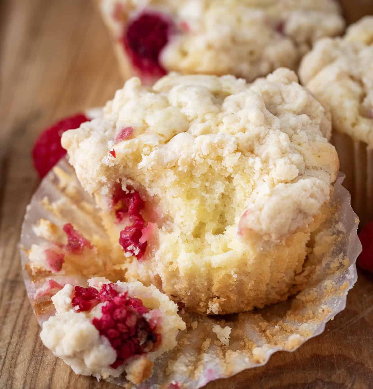 Close up of a bit into Raspberry White Chocolate Chip Muffin showing tender interior.