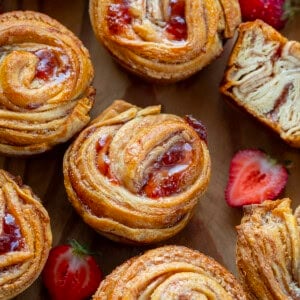 Strawberries and Cream Cruffins on a wooden table with fresh strawberries.