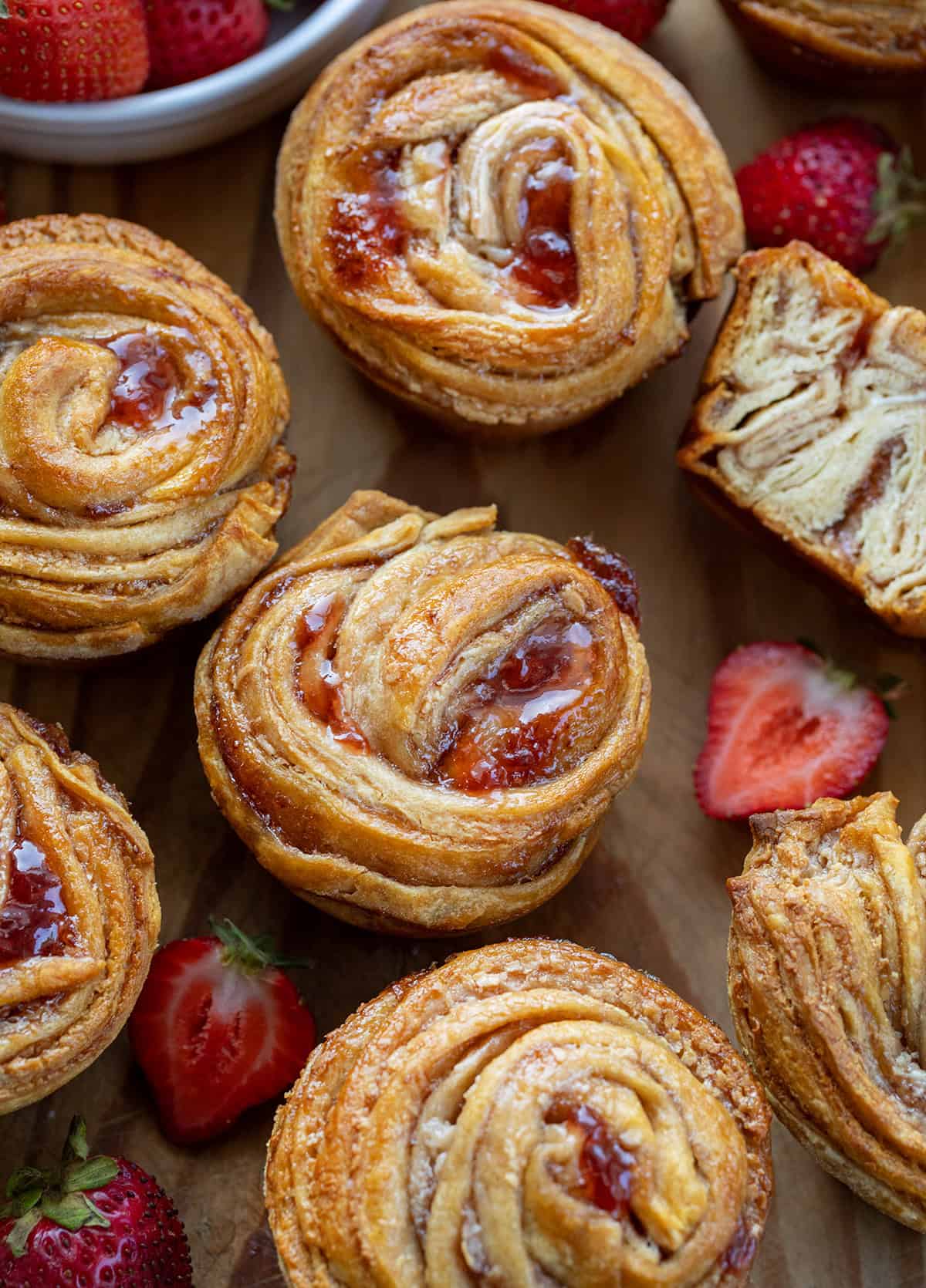 Strawberries and Cream Cruffins on a wooden table with fresh strawberries.