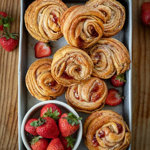 Pan of Strawberries and Cream Cruffins on a wooden table from overhead.