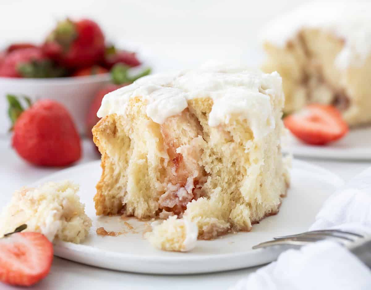 One Strawberry Sweet Roll on a white plate with half of roll removed showing inside texture.