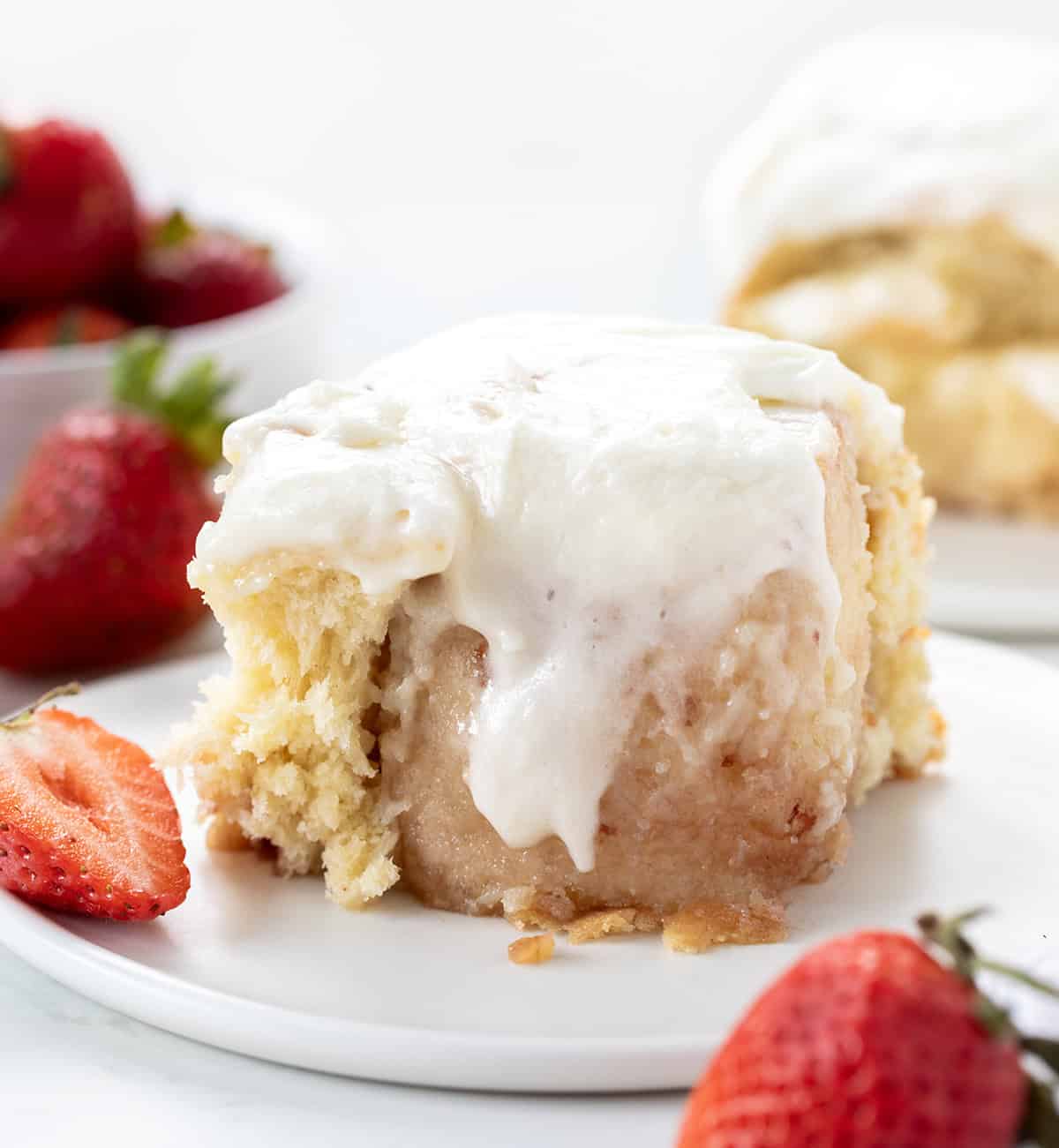 Strawberries and Cream Sweet Roll on a white plate with fresh strawberries.