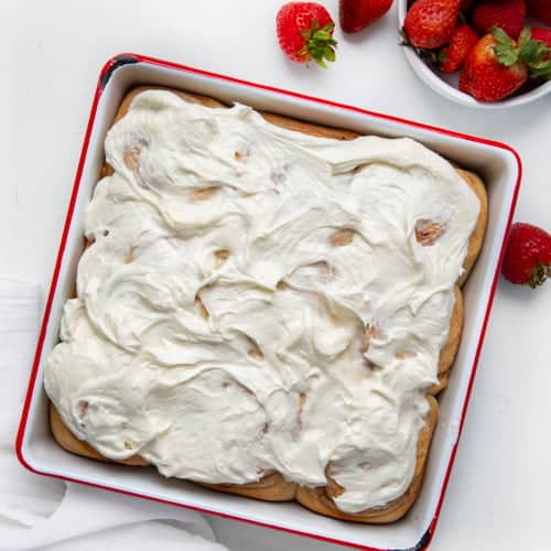 Pan of Strawberries and Cream Sweet Rolls on a white table with fresh strawberries.