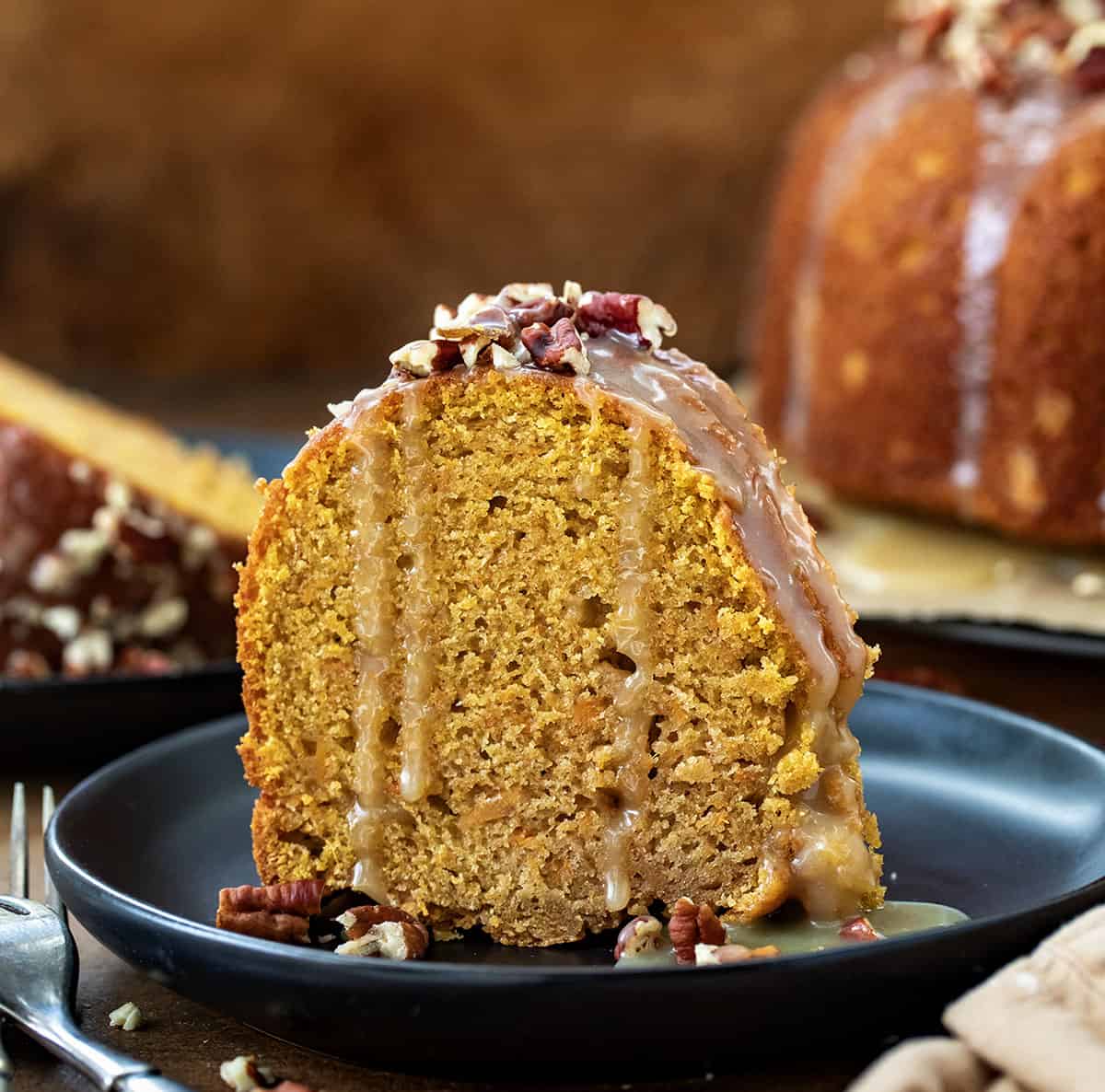 Slice of Sweet Potato Pound Cake on a black plate with glaze dripping down.