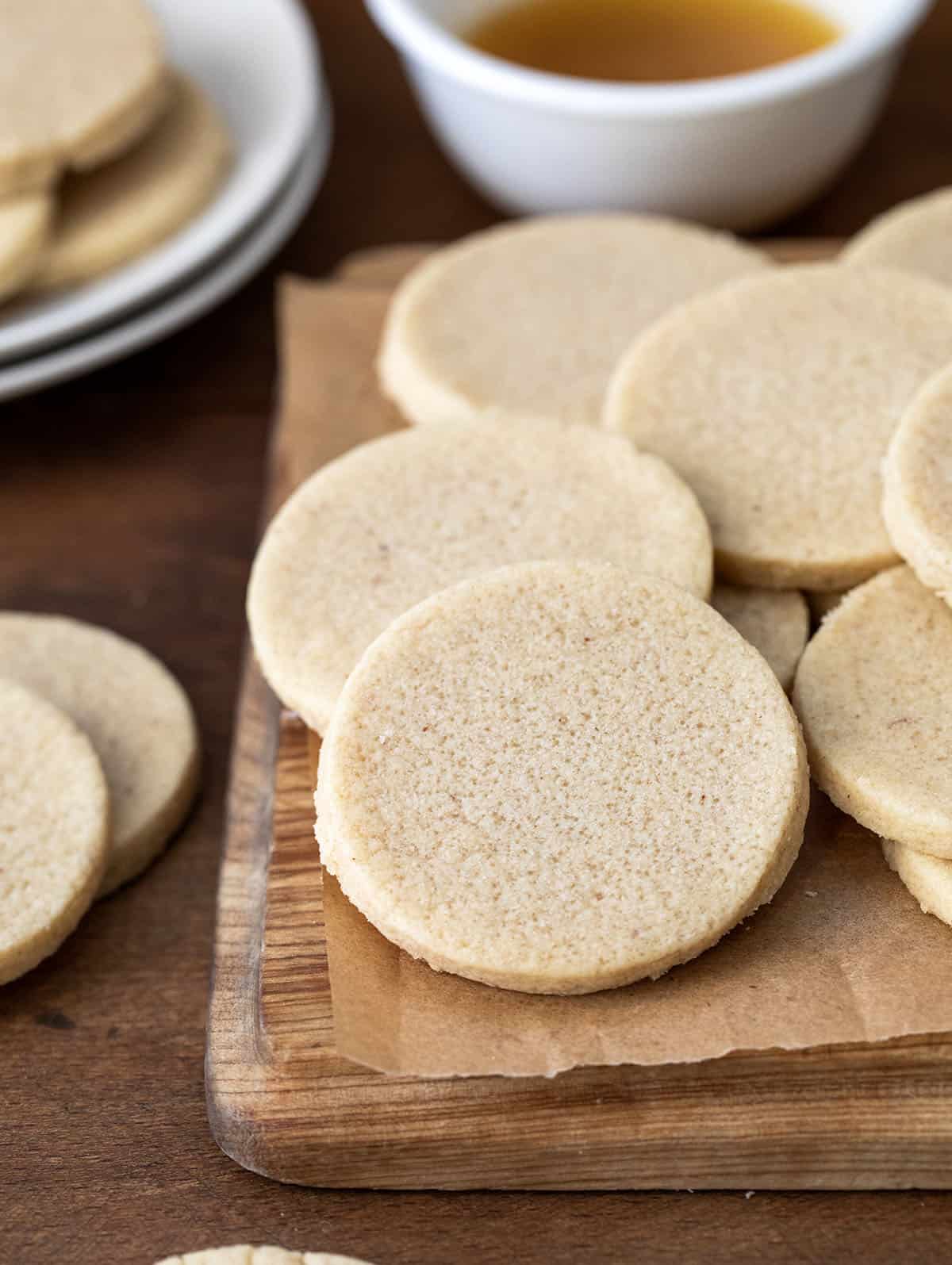 Brown Butter Cut-Out Sugar Cookies laid out on a cutting board with brown butter in the background.