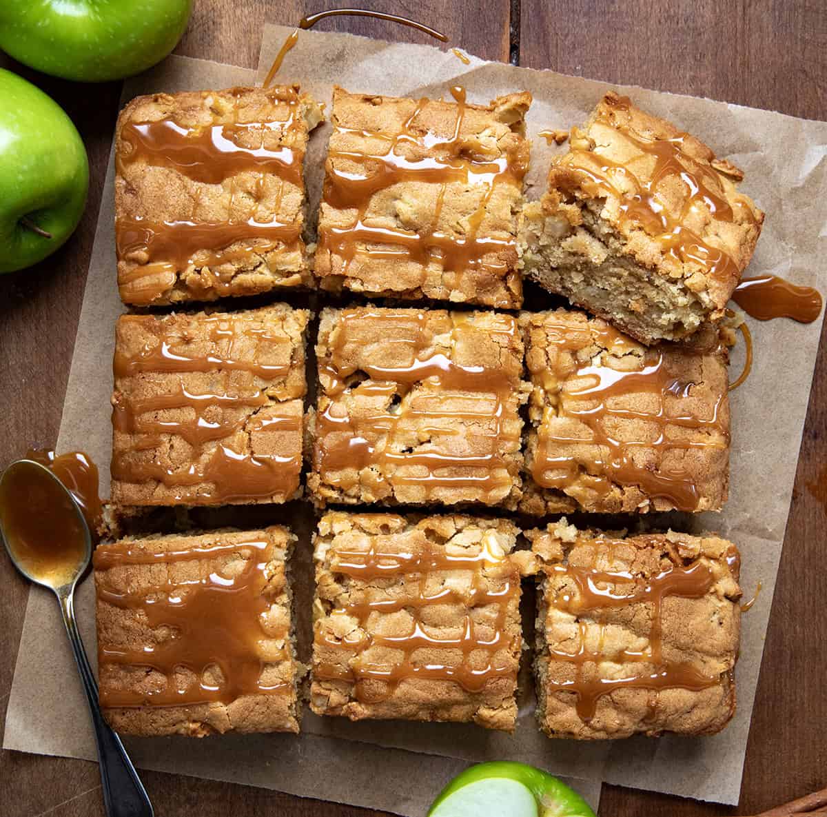 Caramel Apple Snack Cake on a piece of parchment on a wooden table and cut into pieces.