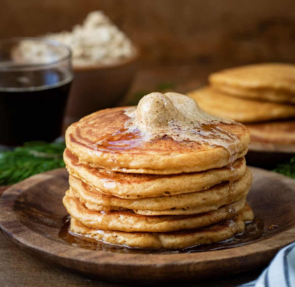 Stack of Gingerbread Pancakes on a wooden plate with gingerbread butter on top.