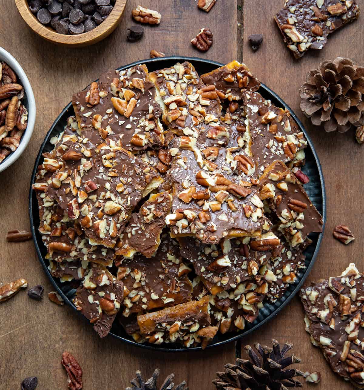 Tray of Maple Pecan Christmas Crack broken into pieces on a wooden table from overhead. 