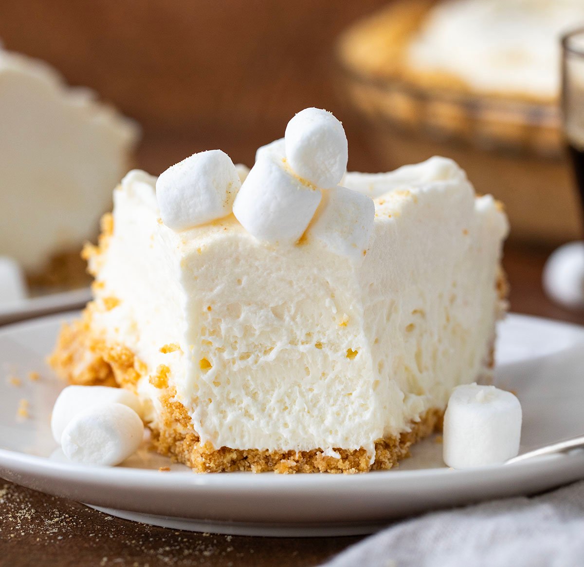 Piece of Marshmallow Cream Cheesecake ona. white plate with a bite taken out and fork resting on plate.