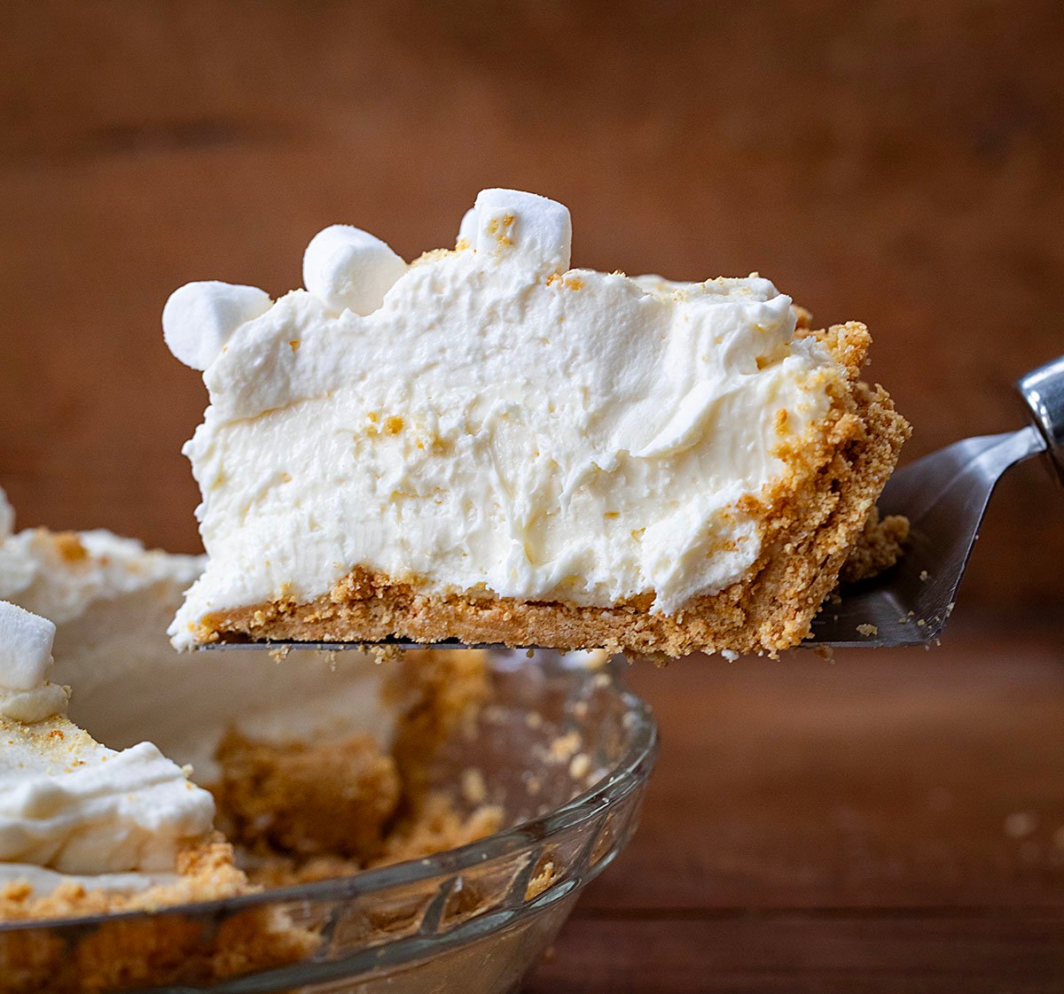 Spatula picking up a piece of Marshmallow Cream Cheesecake from the pie plate. 